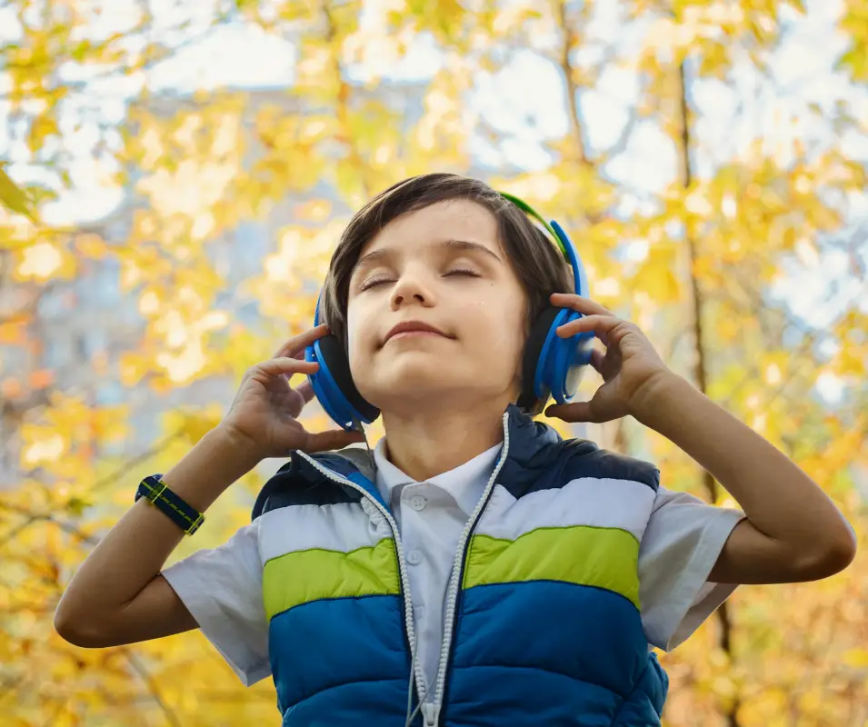 A boy with headphones is listening to music.