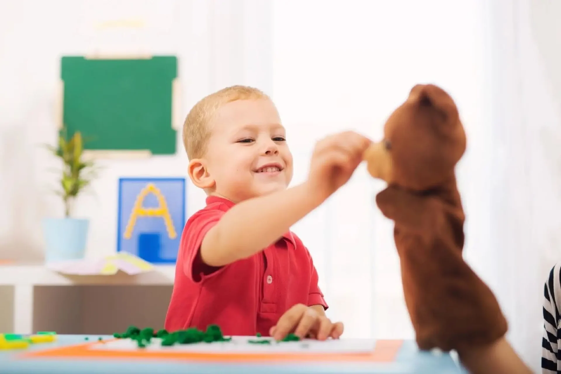 A young boy playing with a teddy bear.