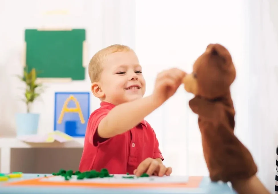 A young boy playing with a teddy bear.